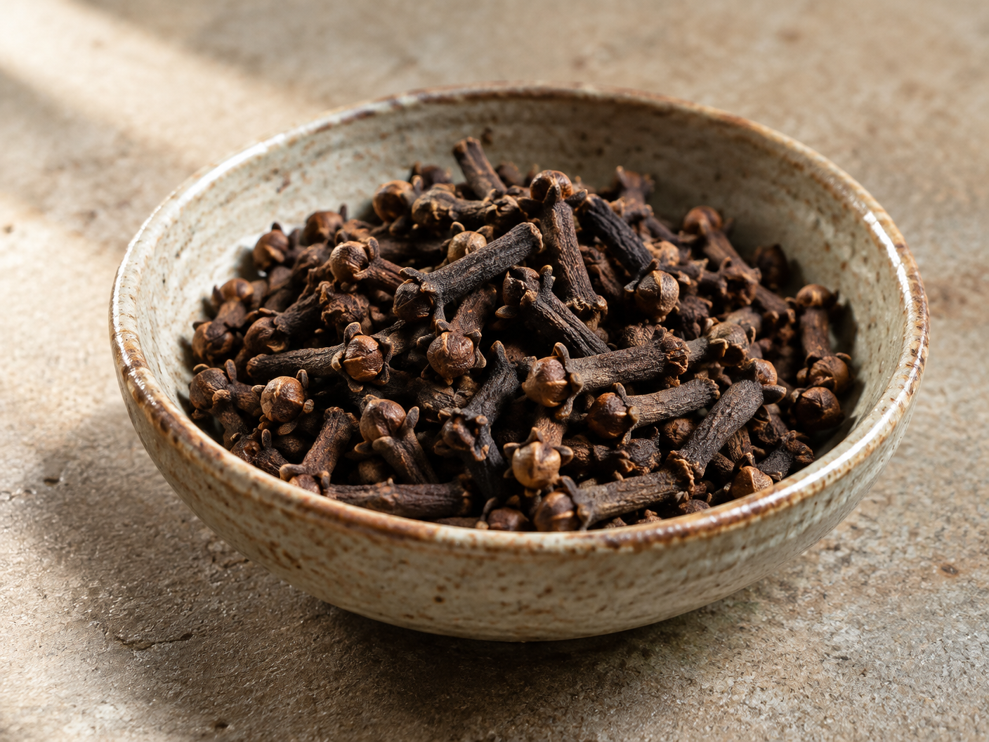 Whole dried cloves in a handmade ceramic bowl